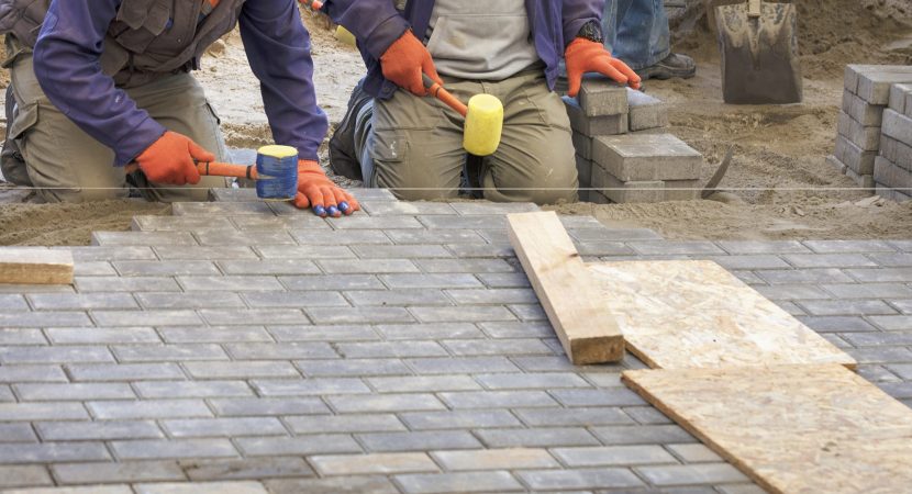 A closeup shot of construction workers laying the paving slab with hammers